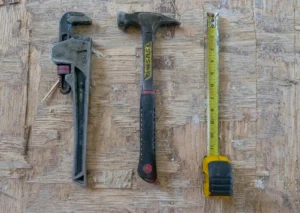 a hammer, a plumbers wrench, and a tape measure